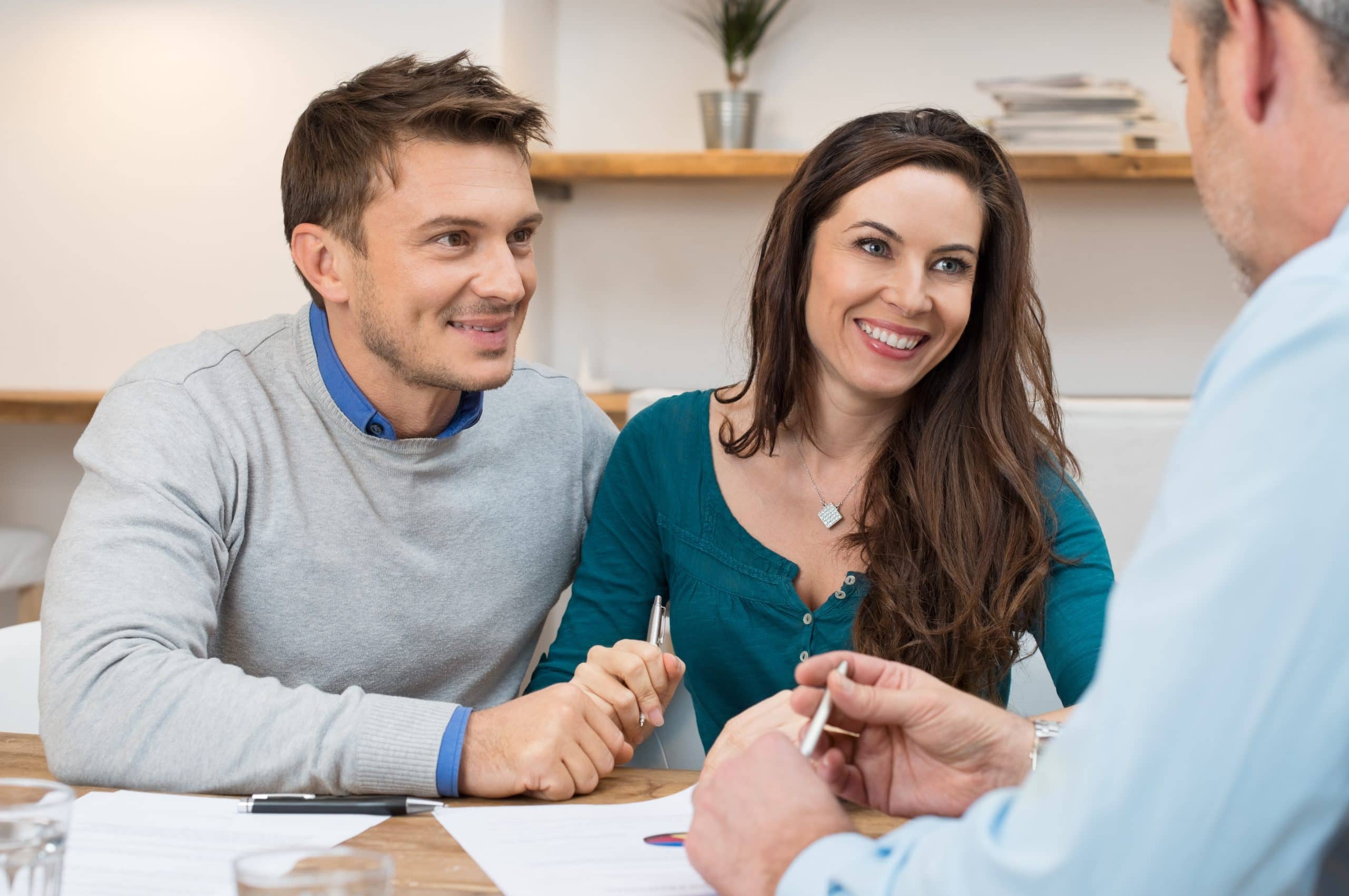 A couple discussing property options with a real estate agent in a professional setting.