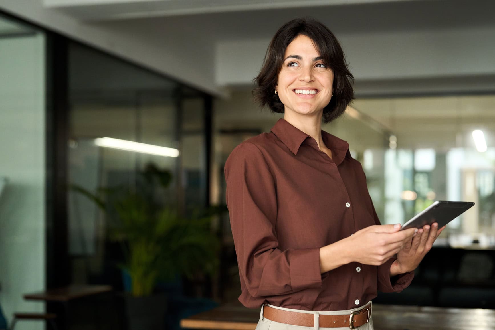 Professional business woman using tab standing in office.